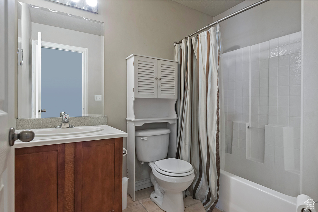 Full bathroom featuring toilet, vanity, shower / bath combo with shower curtain, and tile flooring
