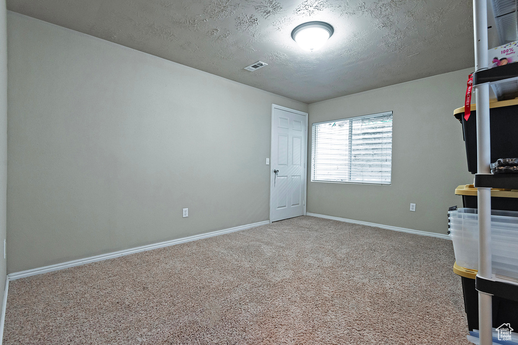 Interior space featuring a textured ceiling and light colored carpet