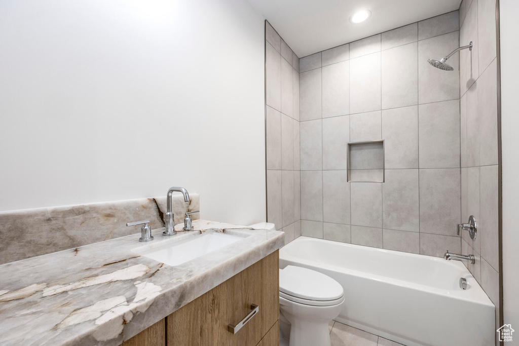 Full bathroom with tiled shower / bath combo, vanity, toilet, and tile flooring