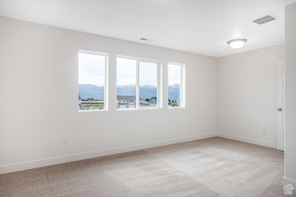 Spare room with a mountain view, light colored carpet, and a healthy amount of sunlight