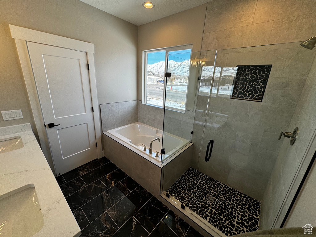Bathroom featuring dual sinks, plus walk in shower, and tile flooring