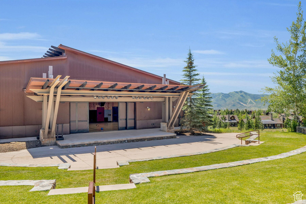 Rear view of property featuring a mountain view, a yard, and a pergola