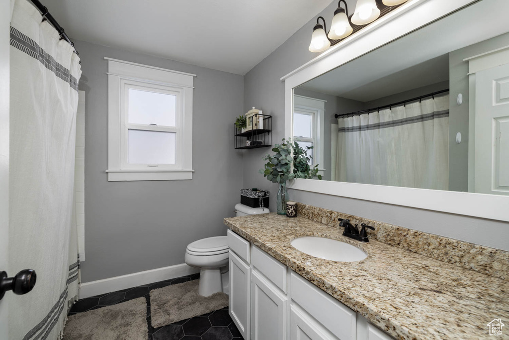 Bathroom featuring tile floors, vanity with extensive cabinet space, toilet, and a healthy amount of sunlight