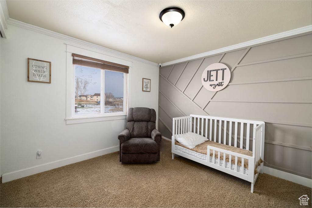 Bedroom with a crib, ornamental molding, and dark colored carpet