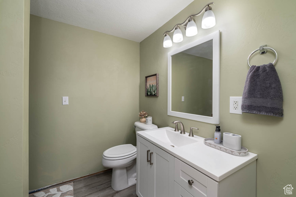Bathroom with a textured ceiling, toilet, vanity, and hardwood / wood-style flooring