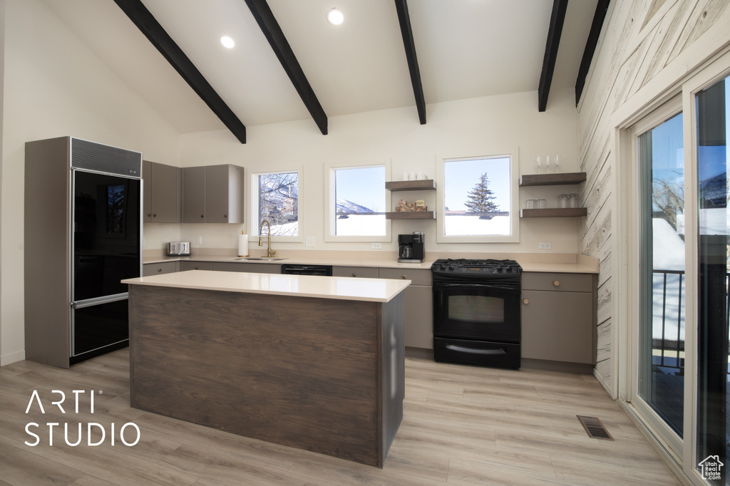 Kitchen with lofted ceiling with beams, a kitchen island, black range with gas stovetop, light hardwood / wood-style floors, and sink