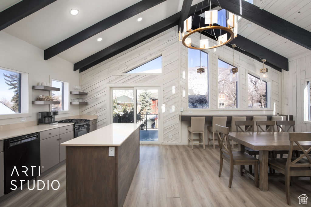 Kitchen featuring light hardwood / wood-style flooring, vaulted ceiling with skylight, black appliances, a notable chandelier, and wooden walls