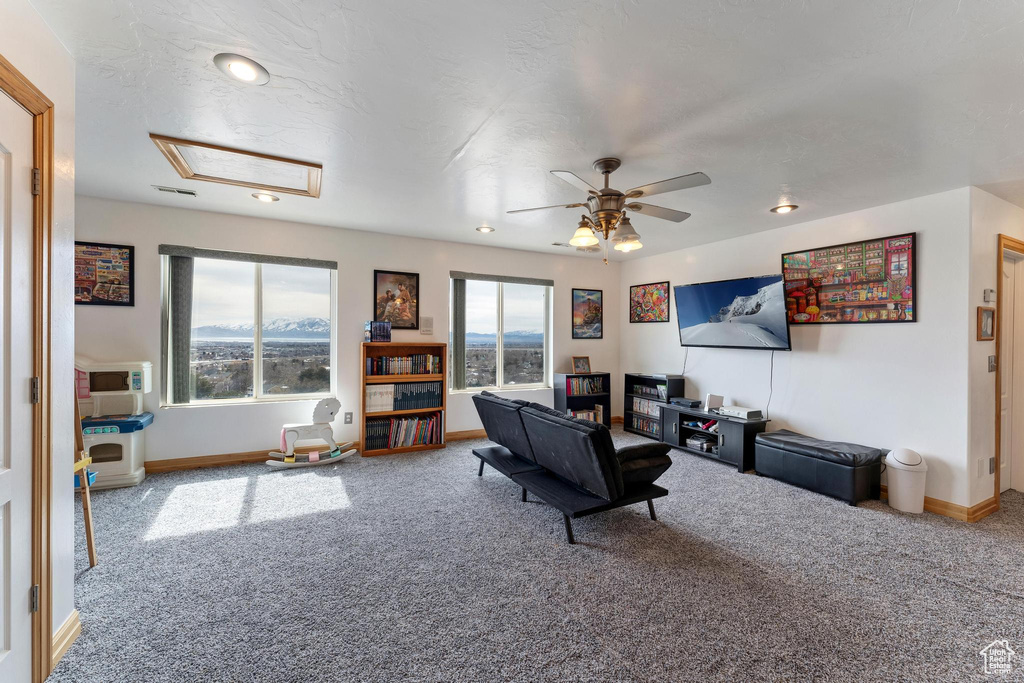 Living room with a skylight, carpet flooring, and ceiling fan