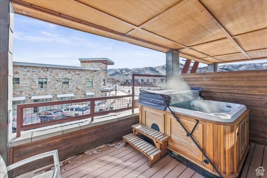Snow covered deck with a mountain view and a hot tub