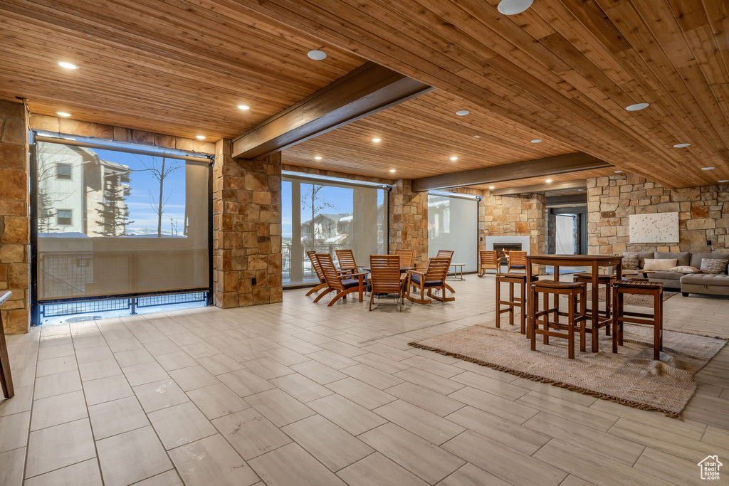 Tiled dining area with a stone fireplace and wood ceiling