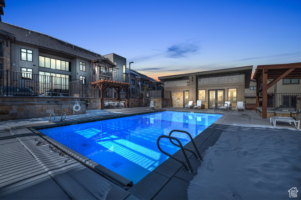 Pool at dusk with a pergola and a patio area