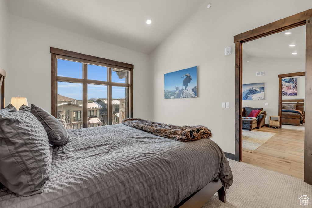 Bedroom with access to exterior, light hardwood / wood-style floors, and high vaulted ceiling