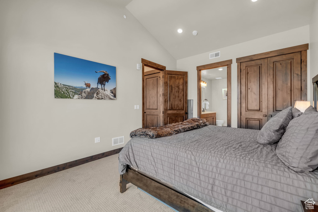 Bedroom featuring carpet floors, connected bathroom, and high vaulted ceiling