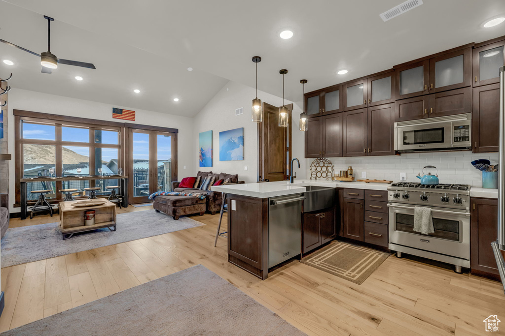 Kitchen featuring lofted ceiling, light hardwood / wood-style floors, appliances with stainless steel finishes, pendant lighting, and ceiling fan