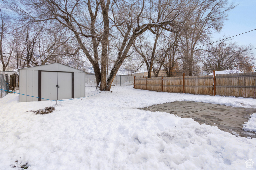 Yard covered in snow featuring a storage unit