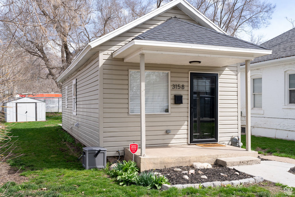Exterior space featuring a front lawn, a storage shed, and central air condition unit