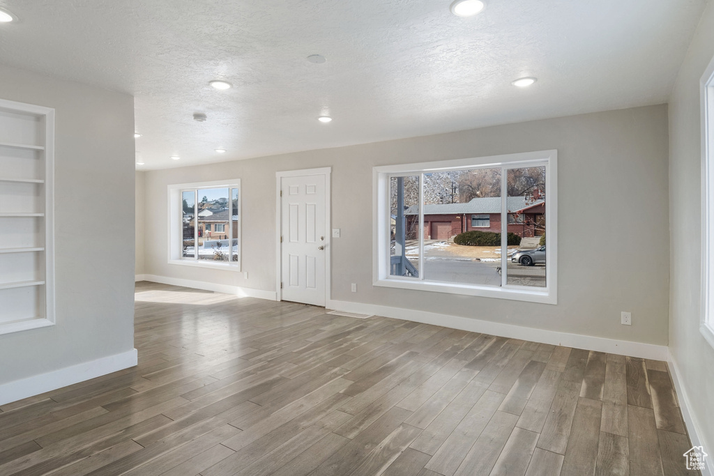 Empty room with built in features, a textured ceiling, and dark hardwood / wood-style floors