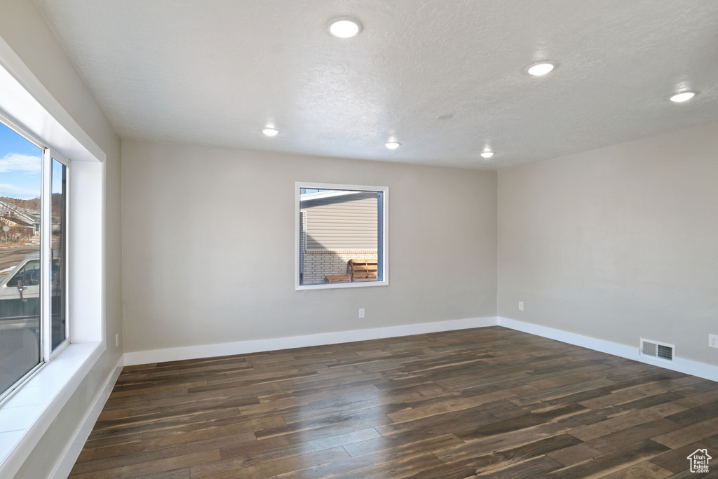 Unfurnished room with dark wood-type flooring and a healthy amount of sunlight