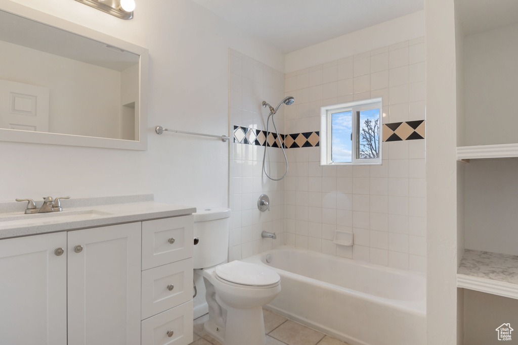 Full bathroom with tiled shower / bath combo, vanity, tile flooring, and toilet