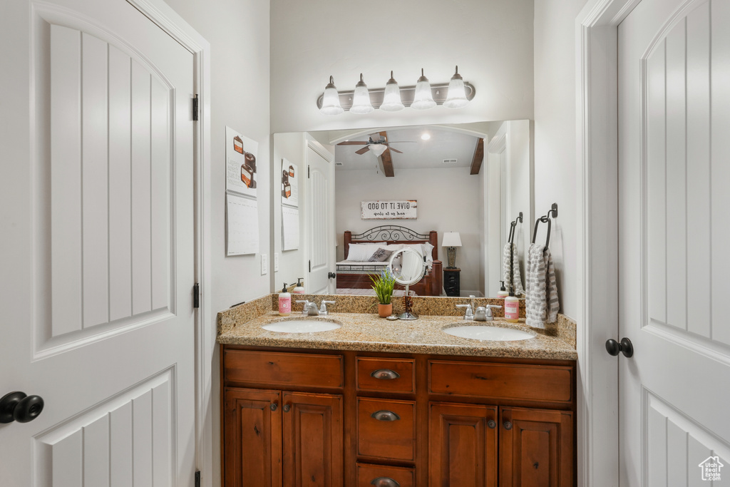 Bathroom with vanity with extensive cabinet space, double sink, and ceiling fan