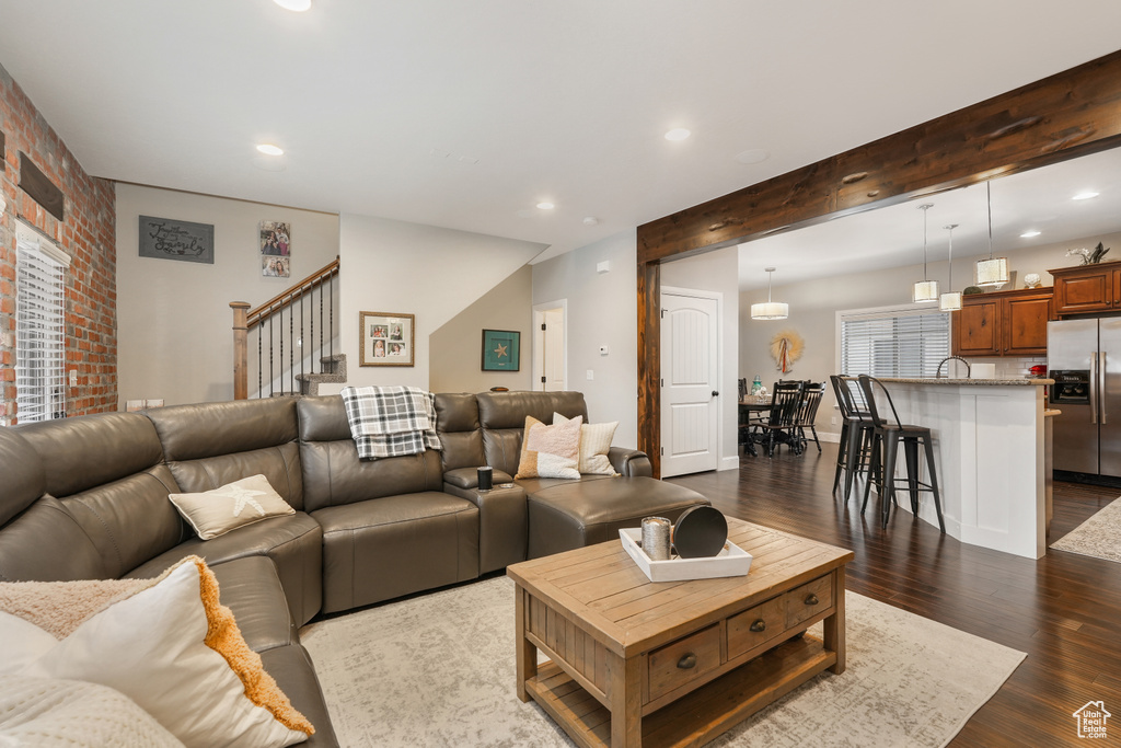 Living room with beam ceiling, dark hardwood / wood-style flooring, brick wall, and sink