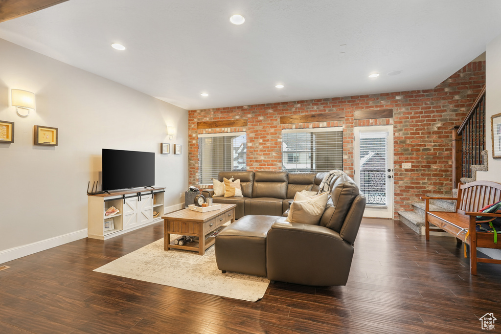 Living room featuring brick wall and dark hardwood / wood-style floors