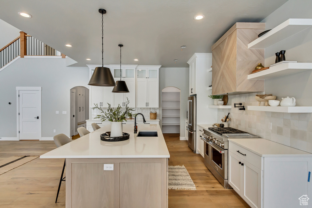 Kitchen featuring a kitchen breakfast bar, backsplash, sink, high quality appliances, and a kitchen island with sink