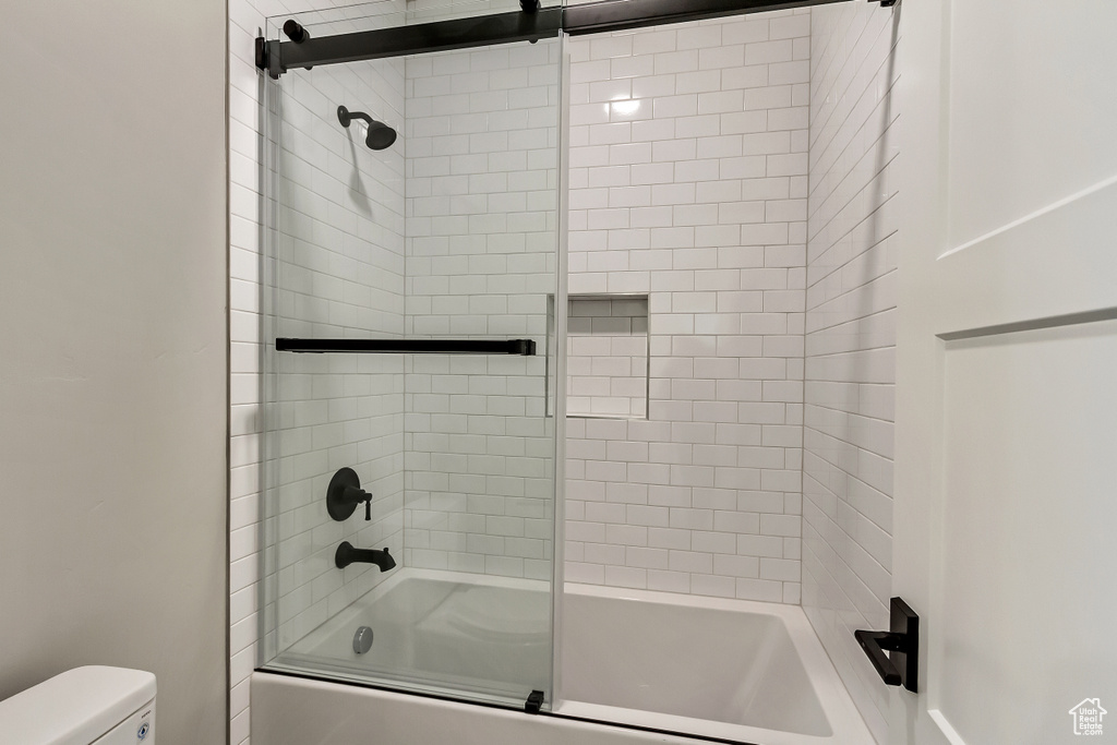 Bathroom with shower / bath combination with glass door and toilet