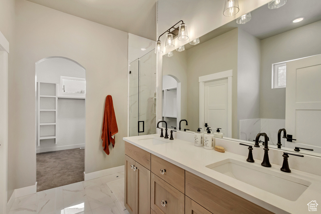 Bathroom with a shower with door, vanity with extensive cabinet space, tile flooring, and double sink