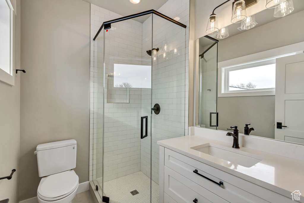 Bathroom featuring oversized vanity, toilet, and a shower with door