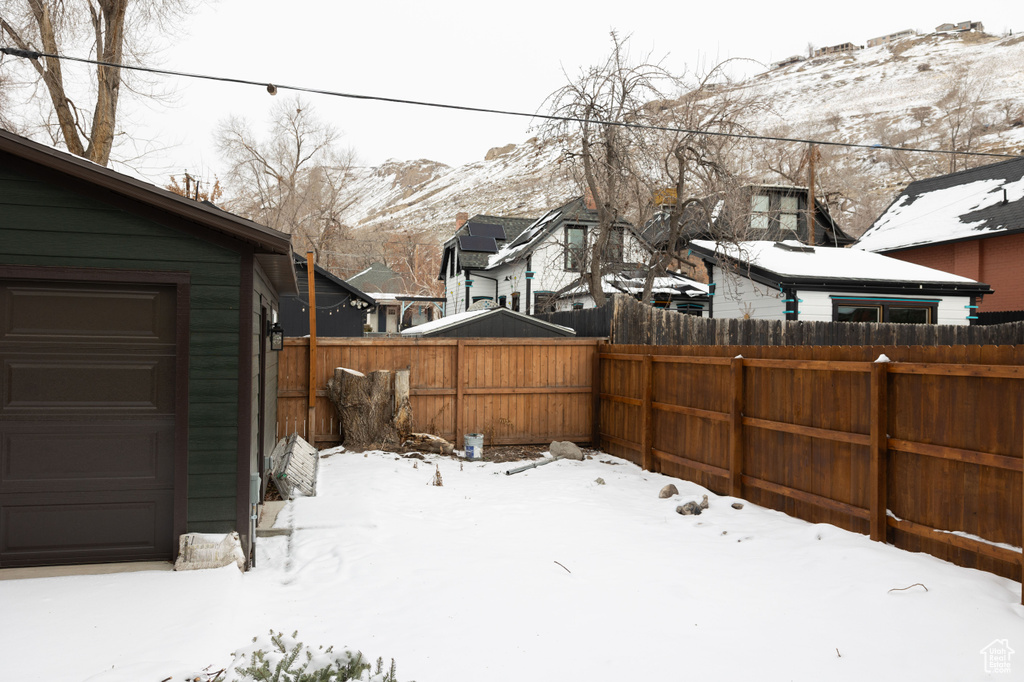 Yard covered in snow with a garage and a mountain view