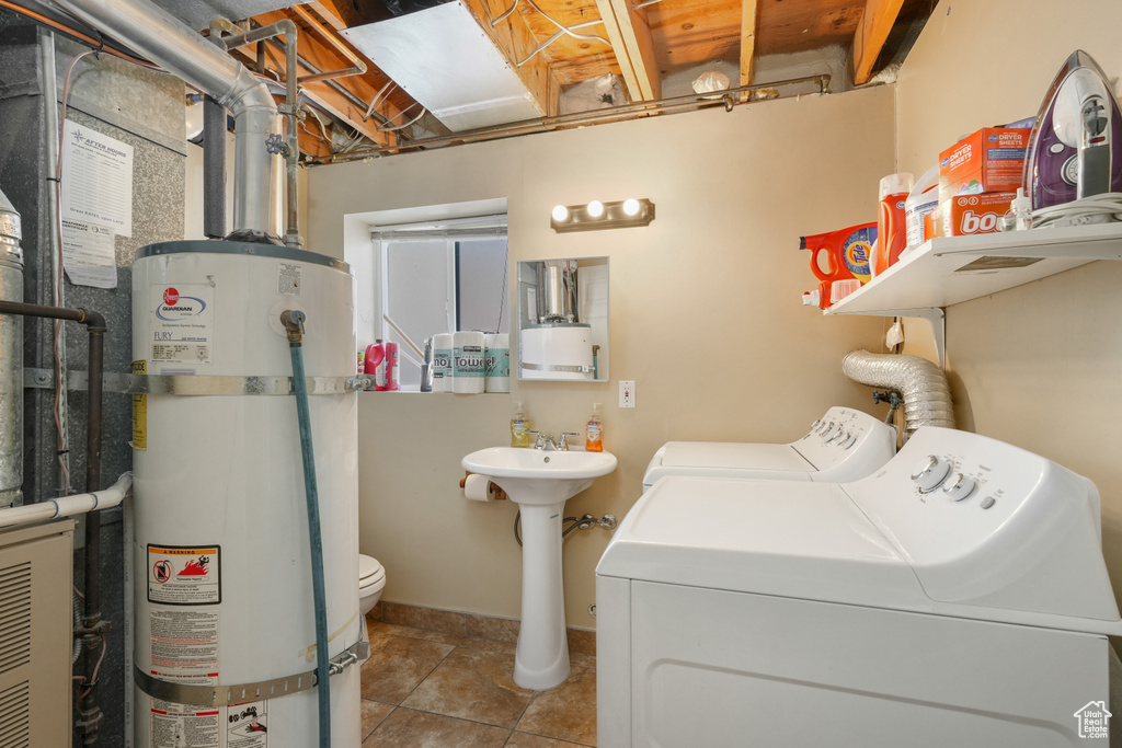 Laundry room featuring water heater, washing machine and dryer, and light tile floors