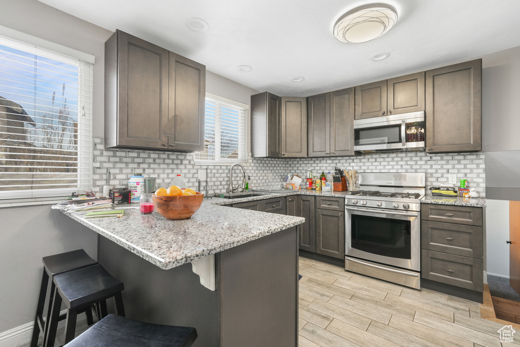 Kitchen with a kitchen breakfast bar, tasteful backsplash, stainless steel appliances, and light stone counters