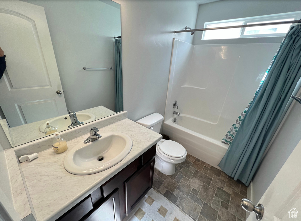 Full bathroom featuring shower / bath combo, tile floors, vanity, and toilet