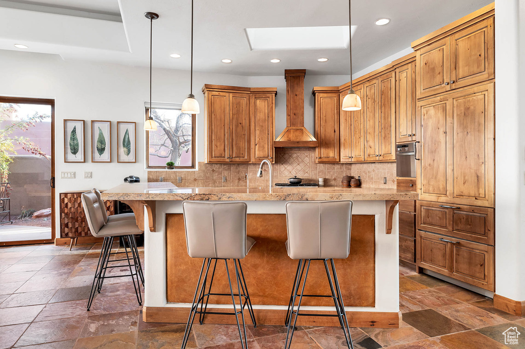 Kitchen with premium range hood, a kitchen breakfast bar, decorative light fixtures, and stainless steel oven