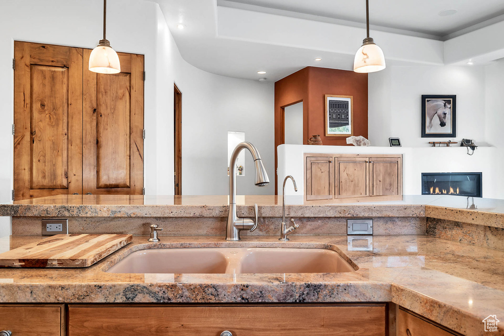 Kitchen with sink, light stone countertops, and hanging light fixtures