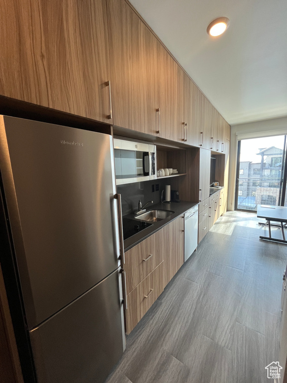Kitchen with sink, stainless steel fridge, dishwasher, and light brown cabinets