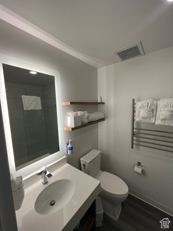 Bathroom featuring toilet, large vanity, hardwood / wood-style flooring, and radiator