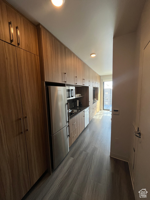 Kitchen with dark hardwood / wood-style floors and appliances with stainless steel finishes