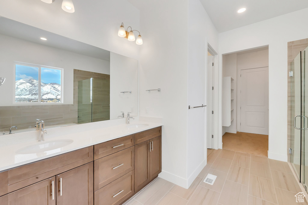 Bathroom featuring oversized vanity, plus walk in shower, tile flooring, and dual sinks