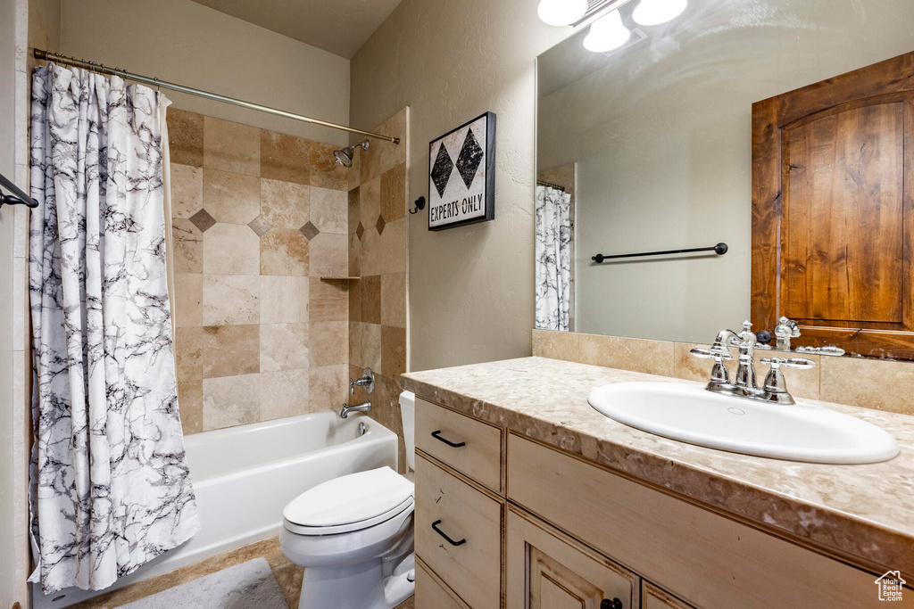 Full bathroom featuring tile floors, toilet, vanity with extensive cabinet space, and shower / tub combo
