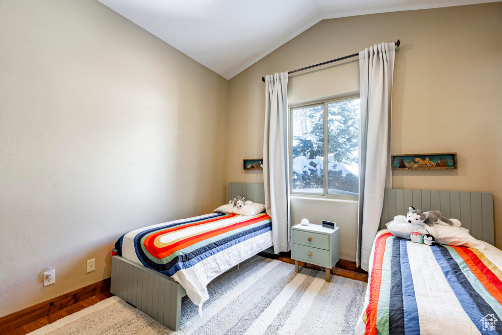 Bedroom featuring lofted ceiling, hardwood / wood-style flooring, and radiator heating unit