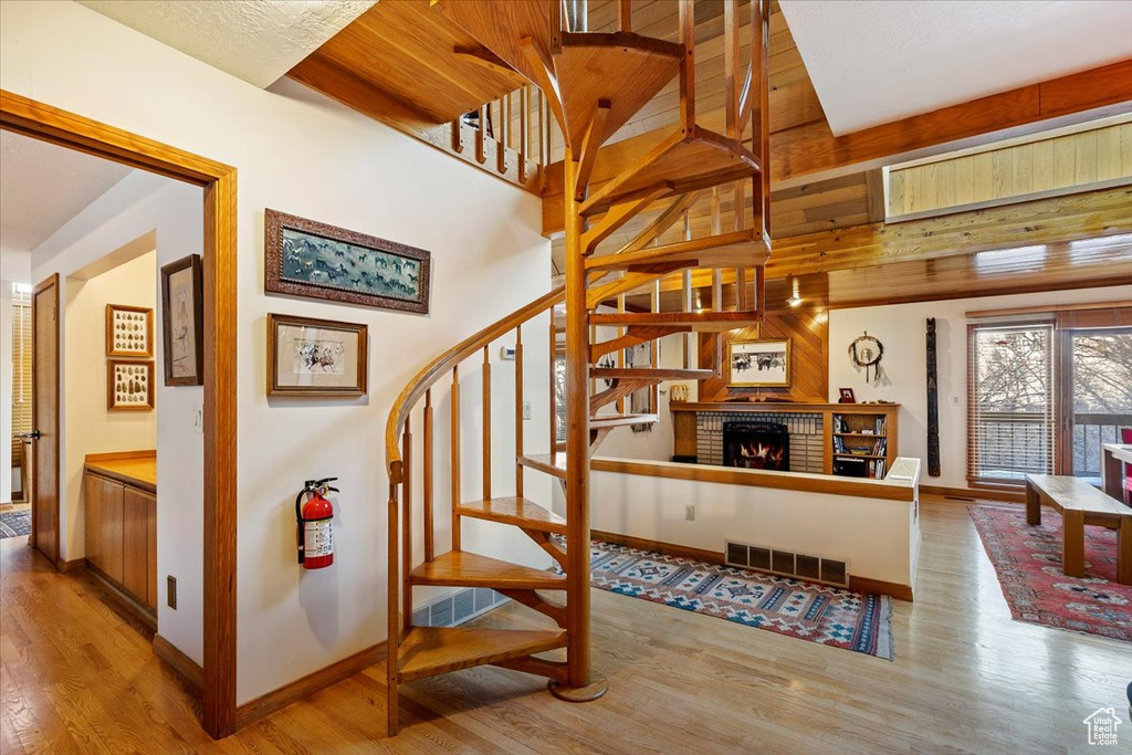 Stairs featuring wood walls, a brick fireplace, and light hardwood / wood-style flooring