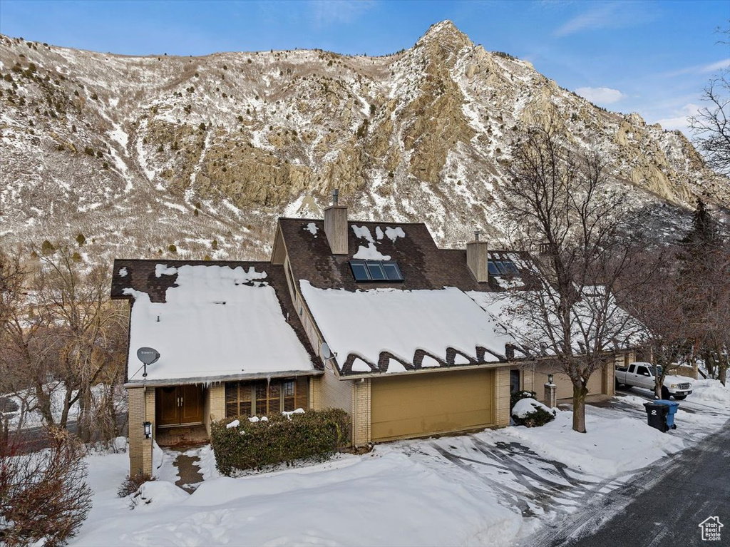 View of snowy exterior featuring a garage and a mountain view