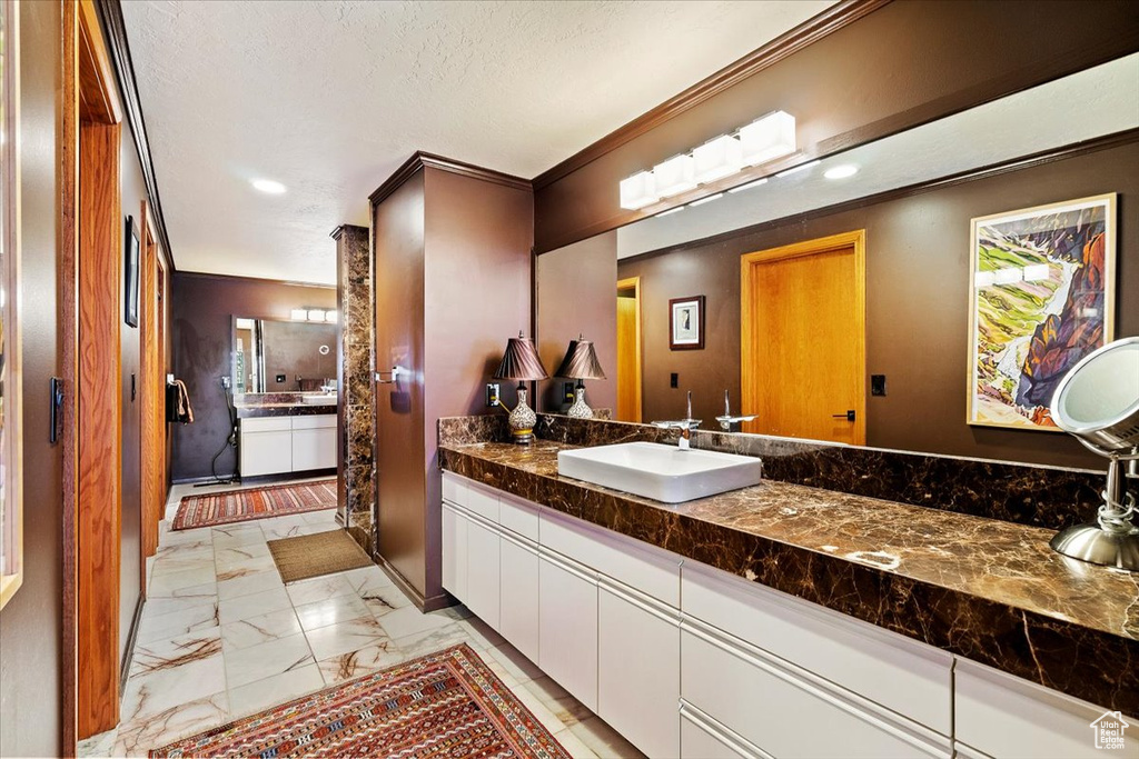 Bathroom with a textured ceiling, tile floors, and large vanity
