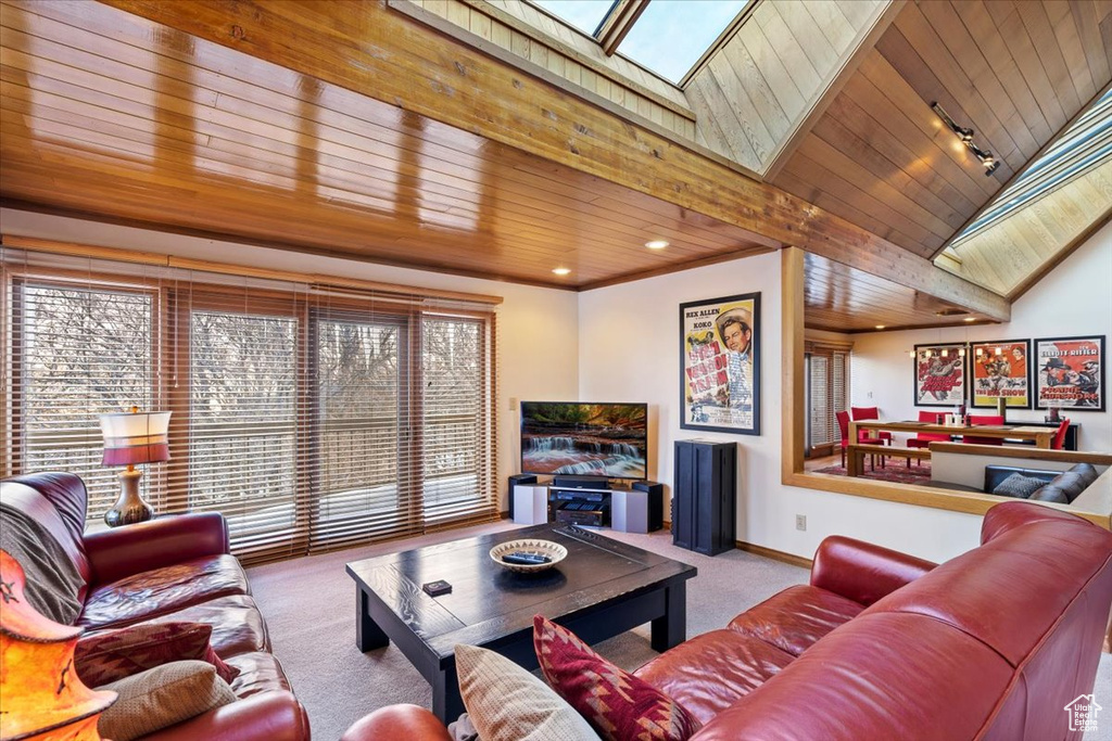 Living room featuring vaulted ceiling with skylight, wooden ceiling, and light colored carpet