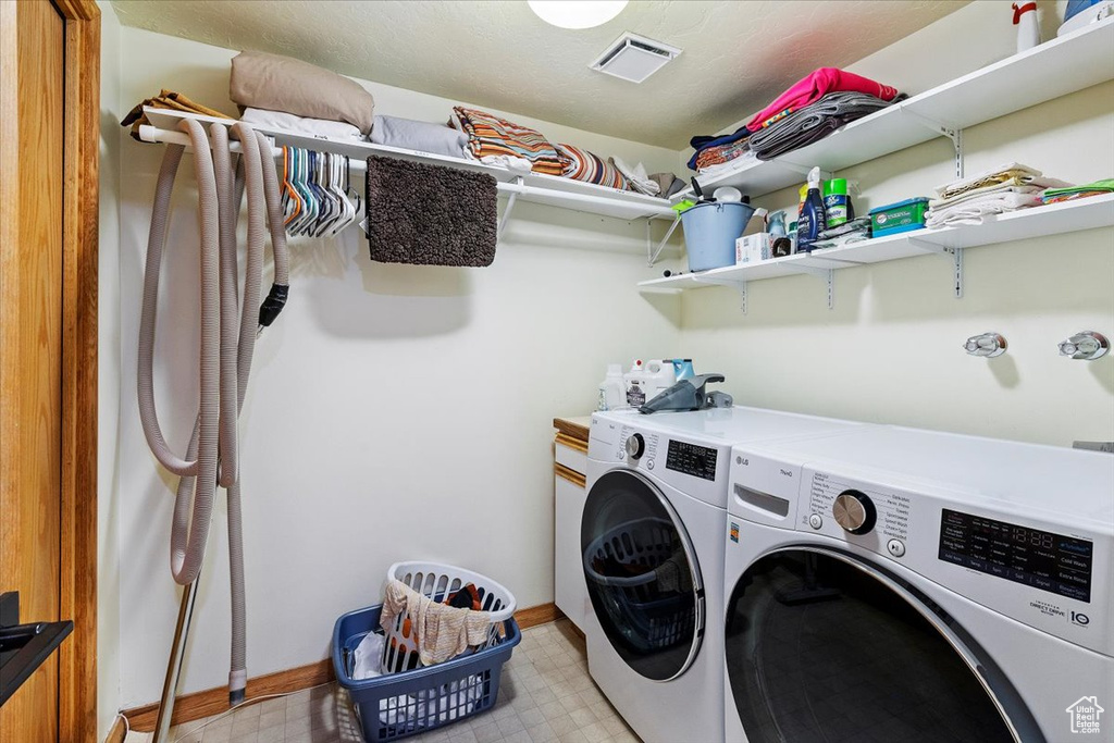 Clothes washing area with light tile floors and washer and dryer