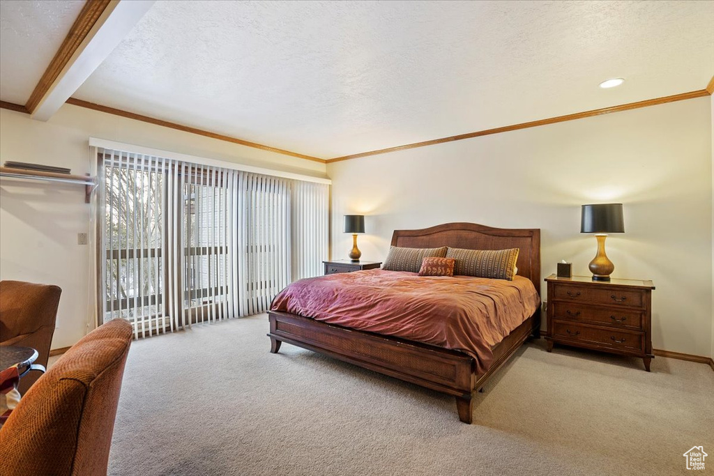 Carpeted bedroom featuring a textured ceiling, ornamental molding, access to exterior, and beam ceiling
