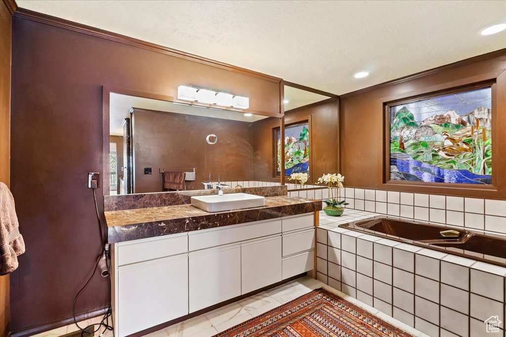 Bathroom featuring tile floors, vanity with extensive cabinet space, and tiled bath
