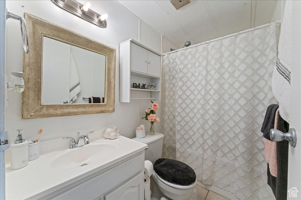 Bathroom with toilet, vanity, a textured ceiling, and tile flooring
